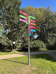 Individueller Fahnenwegweiser (Standrohr, Säule mit 12 Nuten, Nutprofil als Klemmhalter mit individuellen Aluminiumverbund-Fahnen) im Flora-Westfalica-Park in Rheda-Wiedenbrück