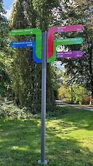 Individueller Fahnenwegweiser (Standrohr, Säule mit 12 Nuten, Nutprofil als Klemmhalter mit individuellen Aluminiumverbund-Fahnen) im Flora-Westfalica-Park in Rheda-Wiedenbrück