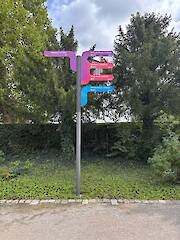 Individueller Fahnenwegweiser (Standrohr, Säule mit 12 Nuten, Nutprofil als Klemmhalter mit individuellen Aluminiumverbund-Fahnen) im Flora-Westfalica-Park in Rheda-Wiedenbrück
