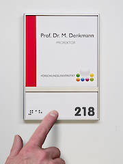 Türschild mit Braillebeschriftung (links) und  taktiler Beschriftung (rechts)